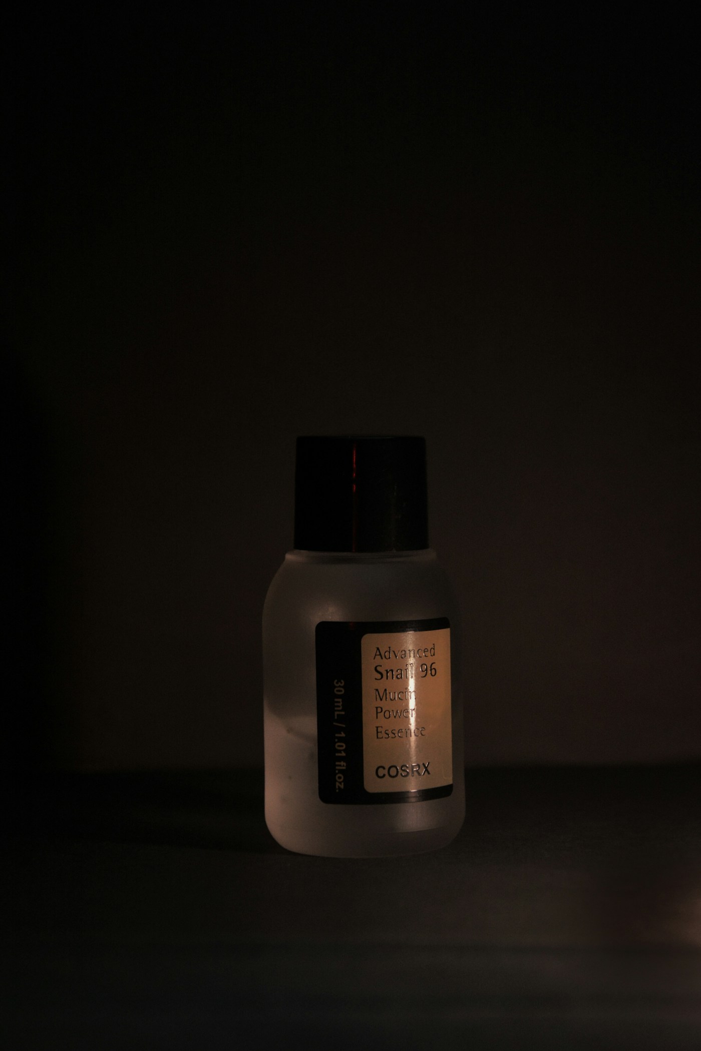 A skincare bottle photographed against a dark green studio background